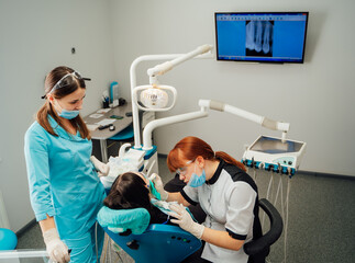 Dental appointment with staff. A young patient receives dental treatment from two professional...