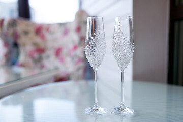 Elegant champagne flutes on a table. Two decorative champagne flutes are placed on a light-colored table, ready for a celebration.