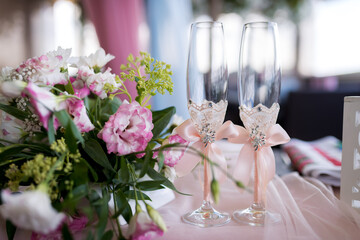 Floral wedding decor. Beautiful floral arrangement beside elegantly decorated champagne glasses set for a wedding celebration.