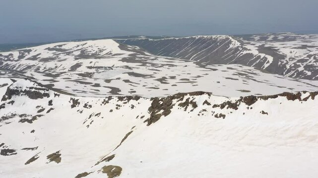 4K aerial drone footage of the snow-covered summits of Mount Aragats, the highest peak in Armenia, with its crater in spring. Breathtaking views of rugged highlands, glaciers, and remote wilderness.