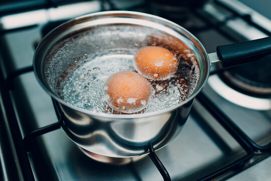 Saucepan stainless steel with boiling eggs breakfast in water on gas stove.