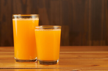Two glasses of freshly squeezed orange juice resting on wooden table