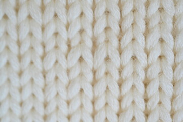 white texture of knitted wool fabric as a background, white smooth symmetrical lines of hand-knitted needlework pattern	
