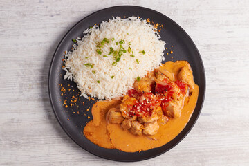 Delicious chicken in peanut sauce with rice and spices on black plate