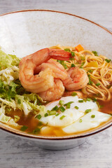 Steaming bowl of ramen with shrimp, egg, and fresh greens