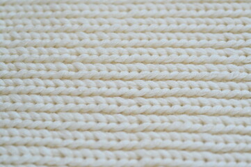 white texture of knitted wool fabric as a background, white smooth symmetrical lines of hand-knitted needlework pattern	
