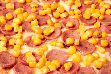 Delicious pizza covered with sausage and corn kernels baking in oven