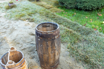 Naklejka premium Barrel is sitting on the ground next to a bucket