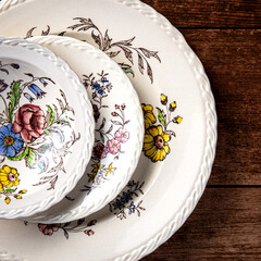 Three antique ornamental plates stacked on a wooden surface.