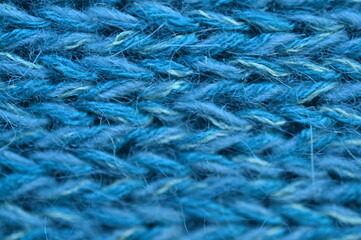 blue texture of knitted wool fabric as a background, smooth symmetrical lines of hand-knitted needlework pattern	
