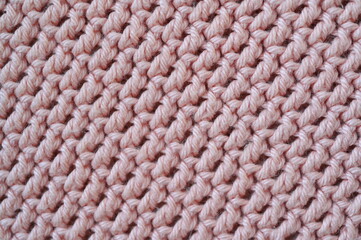 pink crocheted fabric as a background, handmade, close-up of a fragment of a blanket 
