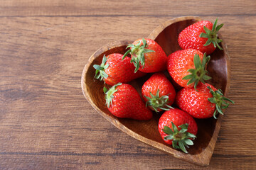 木材背景のハート型の器にいれたイチゴ