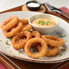 Golden-brown crispy onion rings served with creamy dipping sauces, a delectable appetizer or snack choice.