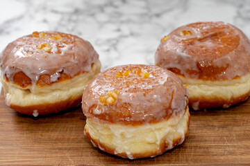 Freshly baked Polish doughnuts (paczki) with a golden-brown crust, glazed with icing and sprinkled with powdered sugar and candied orange peel. A traditional Fat Thursday treat full of flavor.
