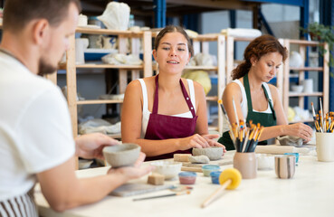 Three students in pottery workshop learn to create homemade plates and other utensils from clay