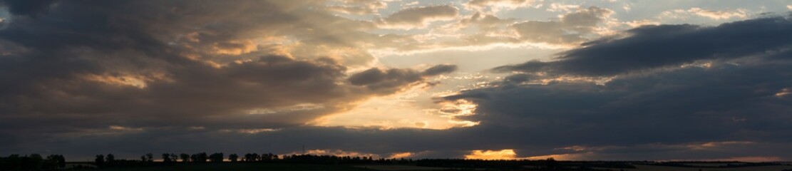Fototapeta premium Landscape at sunset. Tragic gloomy sky. Panorama. Crimson twilight. Heavy, gloomy, dark clouds.