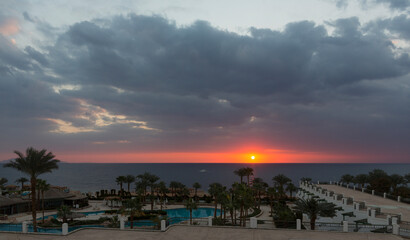 Sunrise on the sea coast. The movement of the sun and clouds across the sky. Park recreation areas of Egypt. Garden and landscape design.