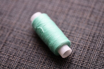 A single spool of thread sitting on a table, possibly for sewing or crafting projects.