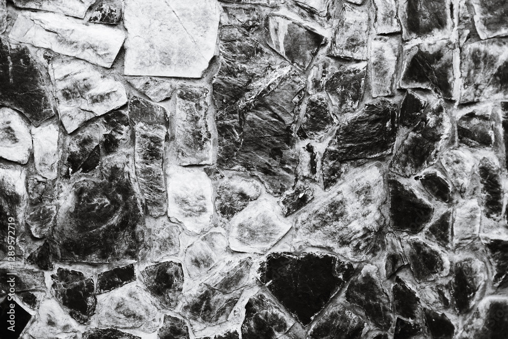 Poster a close-up image of a stone wall in monochrome.