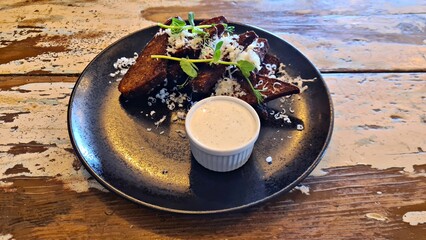 Fried slices of black bread with garlic and white sauce on large plate