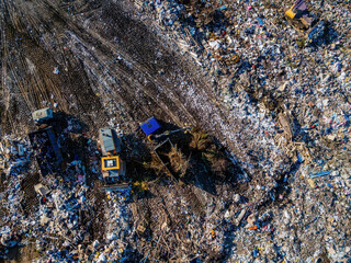 Garbage dump and working dump truck and bulldozer, aerial top view