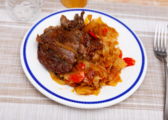 Appetizing pork cheeks with stewed cabbage served on platter