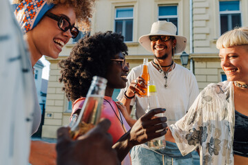 Cheerful friends toasting with drinks while enjoying a summer day together in the city