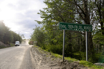 A sign reading "End of the World Station" on the side of a road with a moving van