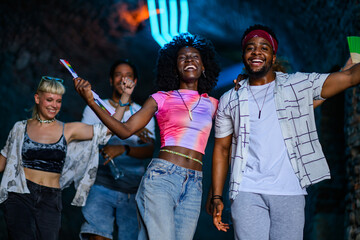 Happy friends dancing and enjoying music festival at night