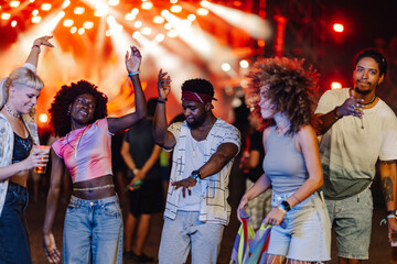 Friends dancing and enjoying music festival at night