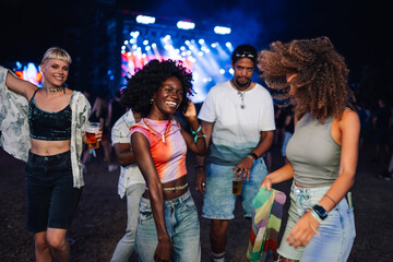 Young people dancing and drinking beer at music festival enjoying nightlife