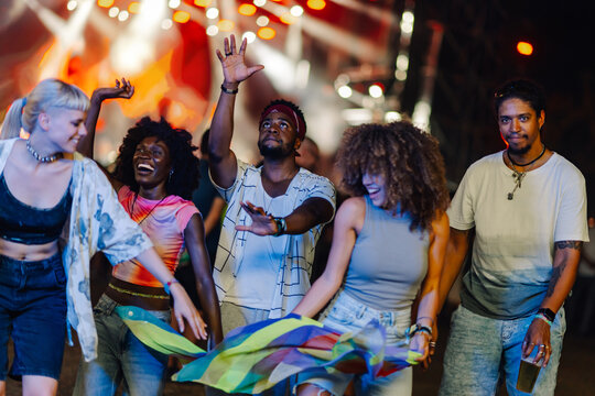 Young people dancing and enjoying music festival at night