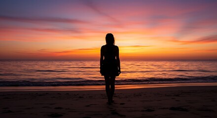 Fototapeta premium Woman Standing on Beach Enjoying Colorful Sunset Over the Ocean
