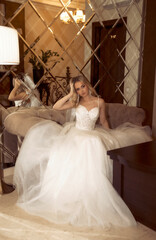 blonde bride with veil, in wedding dress posing in hotel