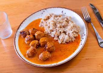 Small portion of oatmeal complements round fried albondigas meatballs made from ground beef in tomato gravy with addition of spicy spices and aromatic herbs