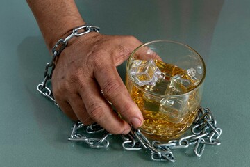 Male hand chained to a glass of alcoholic beverage