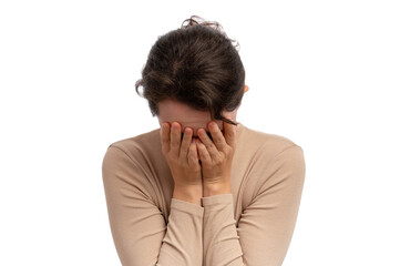 Fototapeta premium A young woman with brown hair covering her face with her hands, expressing sadness against a white background.