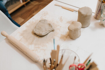 Hands of a female potter making ceramic clay product on the table in the pottery workshop. Potter...