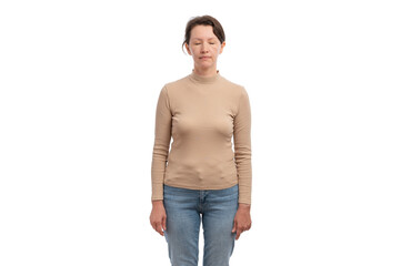 A young woman standing with her eyes closed, wearing a beige long-sleeve top and blue jeans.