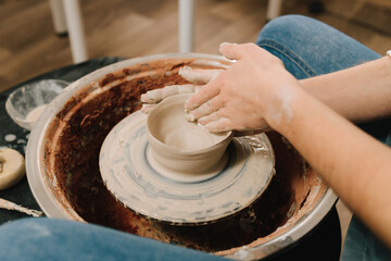 Craftswoman is molding porcelain dish in the pottery studio. Artisan sculpts a pottery plate on the...