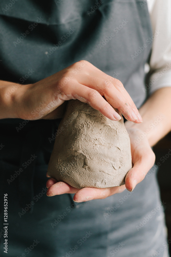 Poster Process of creating ceramic products. Potter holds a piece of wet clay in their hands, molds it into form.