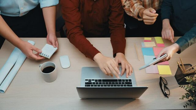 A modern office scene featuring a business team collaborating on a project. Laptops, documents, and coffee cups are scattered across the table, demonstrating teamwork and focus. SACTR