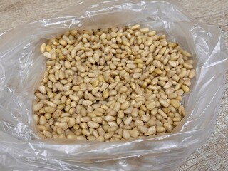 The kernels of peeled pine nuts in a transparent plastic bag for sale by weight on the market....