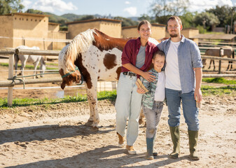 Young man, young woman and boy with brush at horse paddock