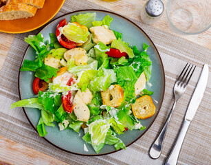 Tasty Caesar salad of grilled chicken breast, greens, tomato, cheese and croutons