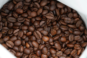 Dive into the rich, aromatic world of freshly roasted coffee beans with this captivating stock photo. Featuring a close-up view of dark, glossy coffee beans nestled in a pristine white container.