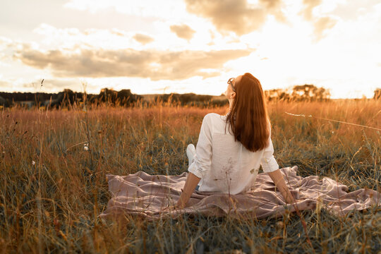 Happy young woman relaxing in nature field summer sunset 