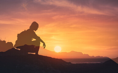 Silhouette of man on a mountain looking out to the sunrise feeling at peace in nature 