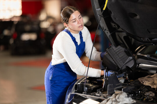 Female auto mechanic changing air filter in car engine
