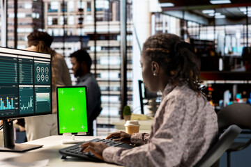 Woman at her desk working on data analysis next to mockup display, engaged in business tasks and budget management to drive effective corporate strategy. Analyst reads reports numbers.